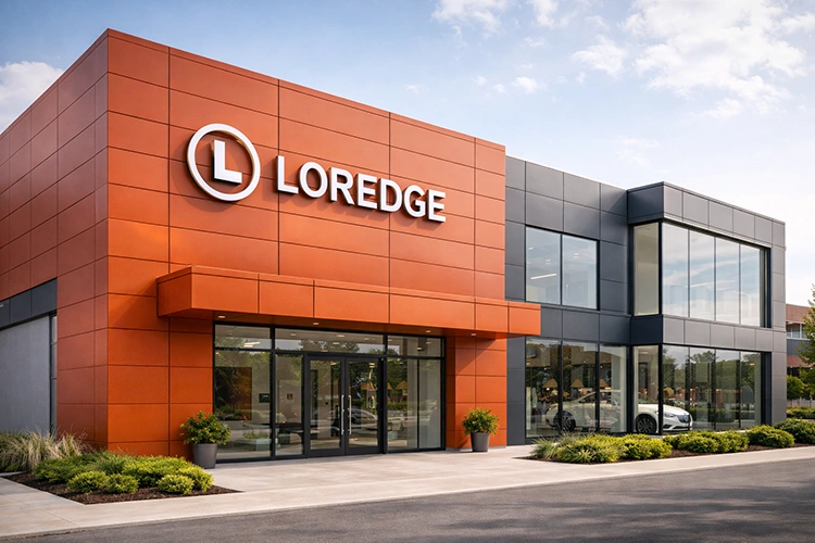 Commercial showroom facade with orange ACP sheet cladding, dark grey panels, and large glass entrance